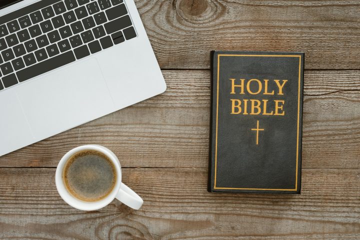 top view of holy bible with laptop and coffee on wooden table